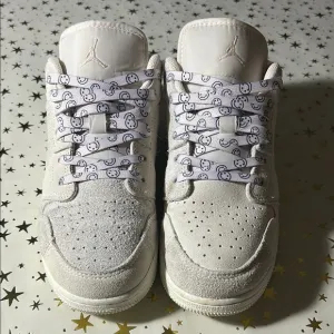 Nike Jordan 1 Low craft series (white) with smiley face shoelaces.